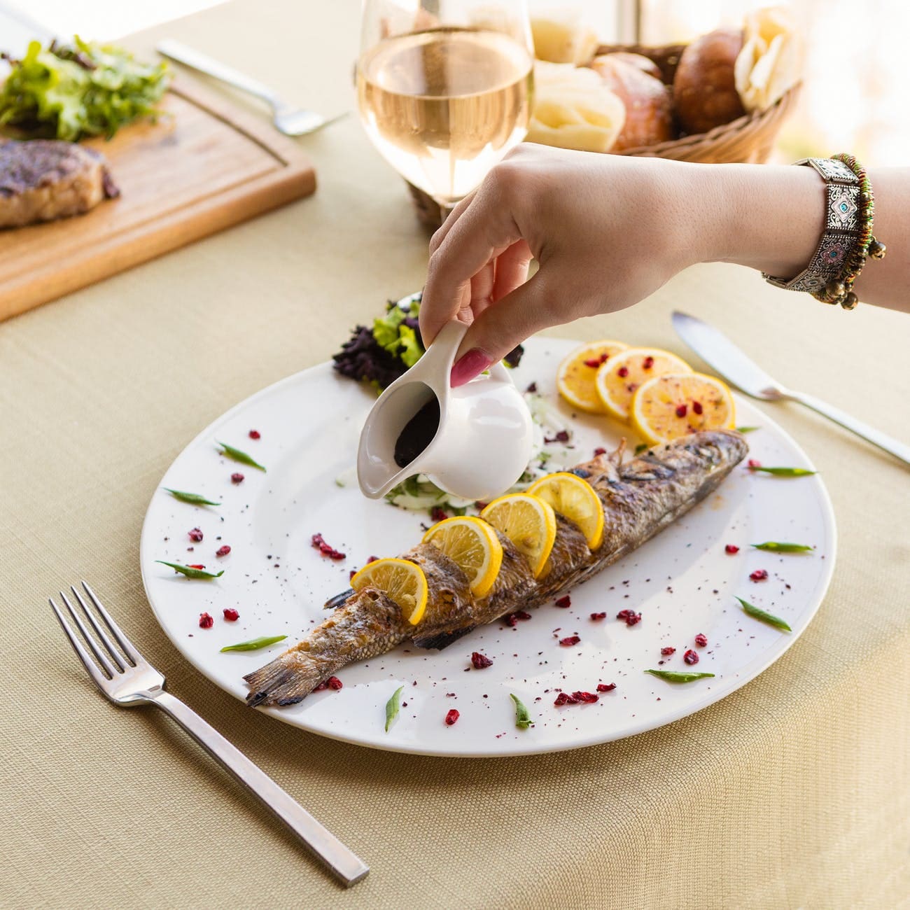 person holding stainless steel fork and bread knife on white ceramic plate