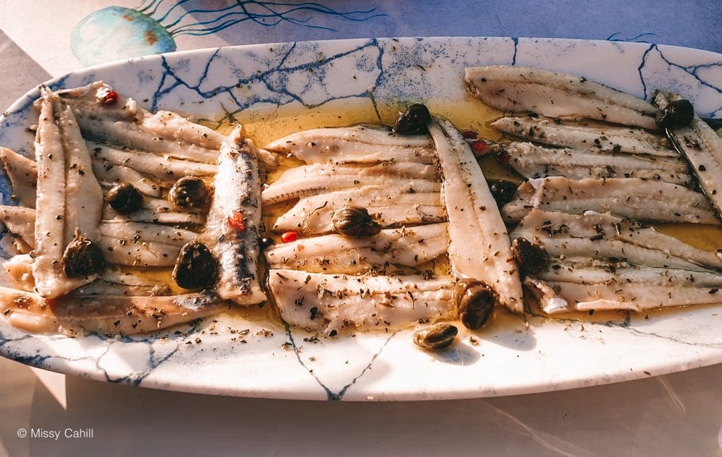 A plate of sardines in olive oil with capers.