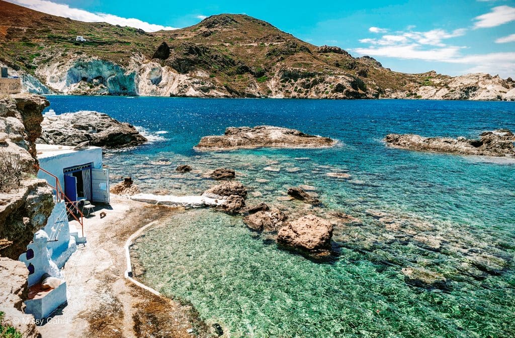 A view over the water of Mandrakia Milos with a fishermans hut visable in the foreground.