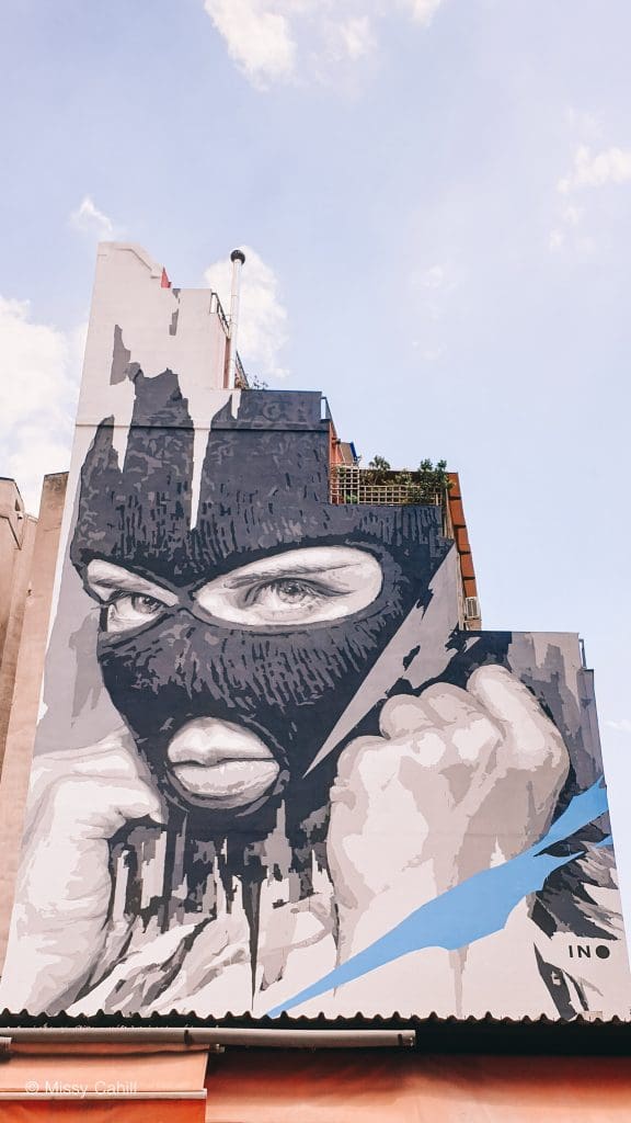Art Work on the side of a building in Athens of a woman in a balaclava.