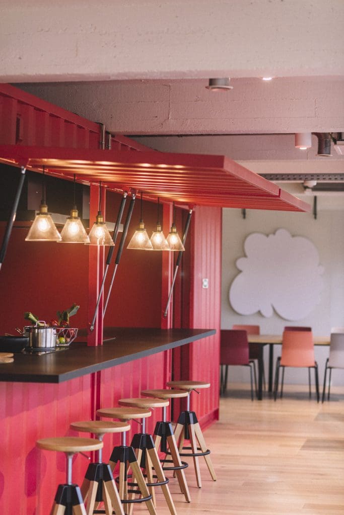 The red shipping container inside The Brain Embassy - a Coworking Space in Antwerp offers stools and drinks for people to connect over.