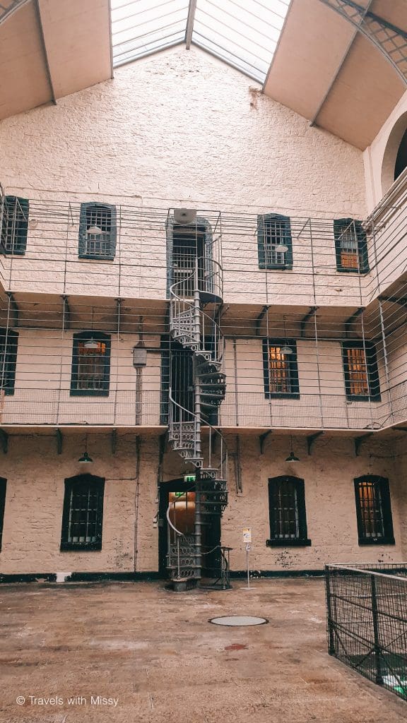 Inside Kilmainham Gaol is white walls and a spiral metal staircase.
