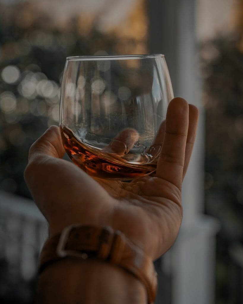 A hand holding a tumbler of whiskey.