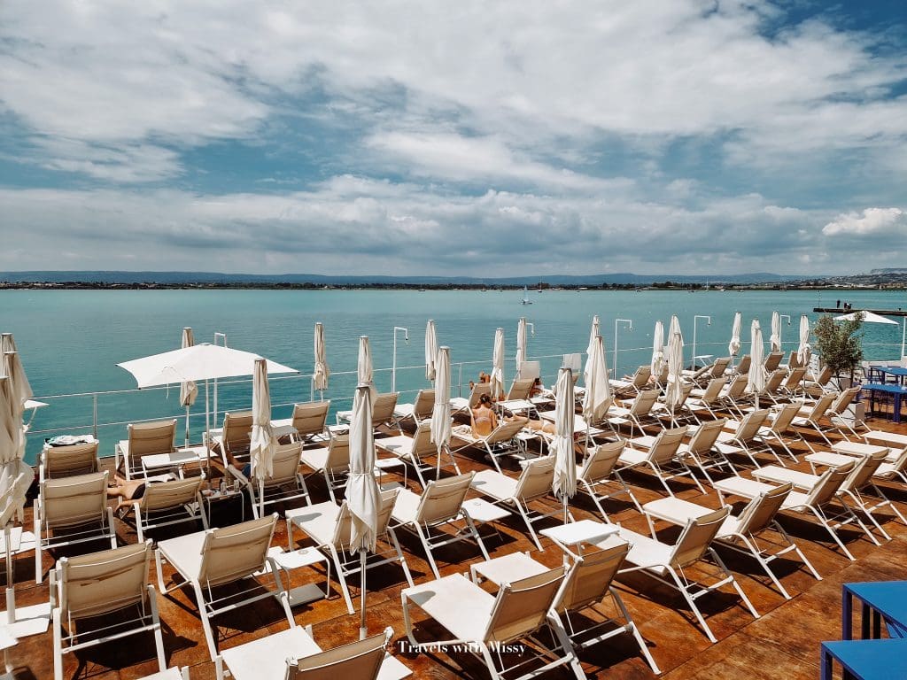 Rows of white sun loungers and umbrellas in Zefiro Solarium in Ortigia Sicily.