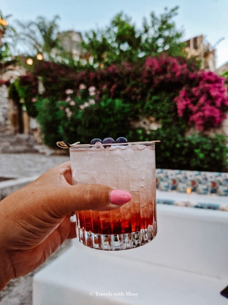 The cocktail 'Bramble' held up from the cocktail bar Chapeau! one of the best bars in Taormina.