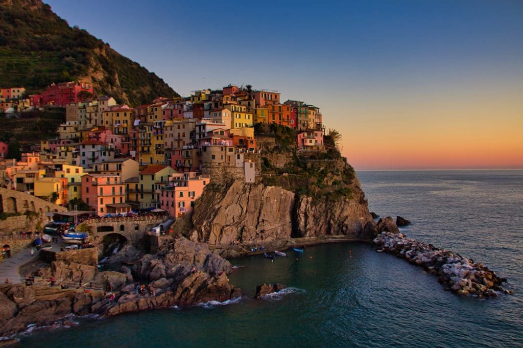 The sun sets behind the town of Manarola, one of the Cinque Terre towns. The colour from the sinking sun illuminates the colours of the decorative buildings.