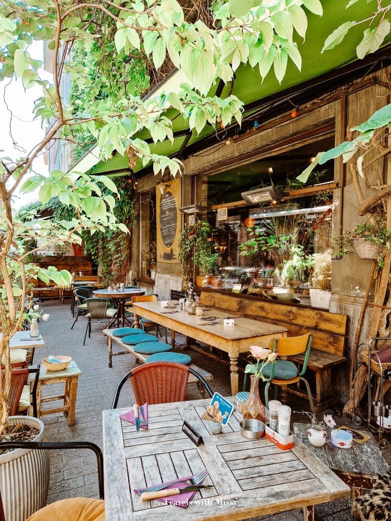 An electic number of tables with mismatched chairs underneath a green awning.